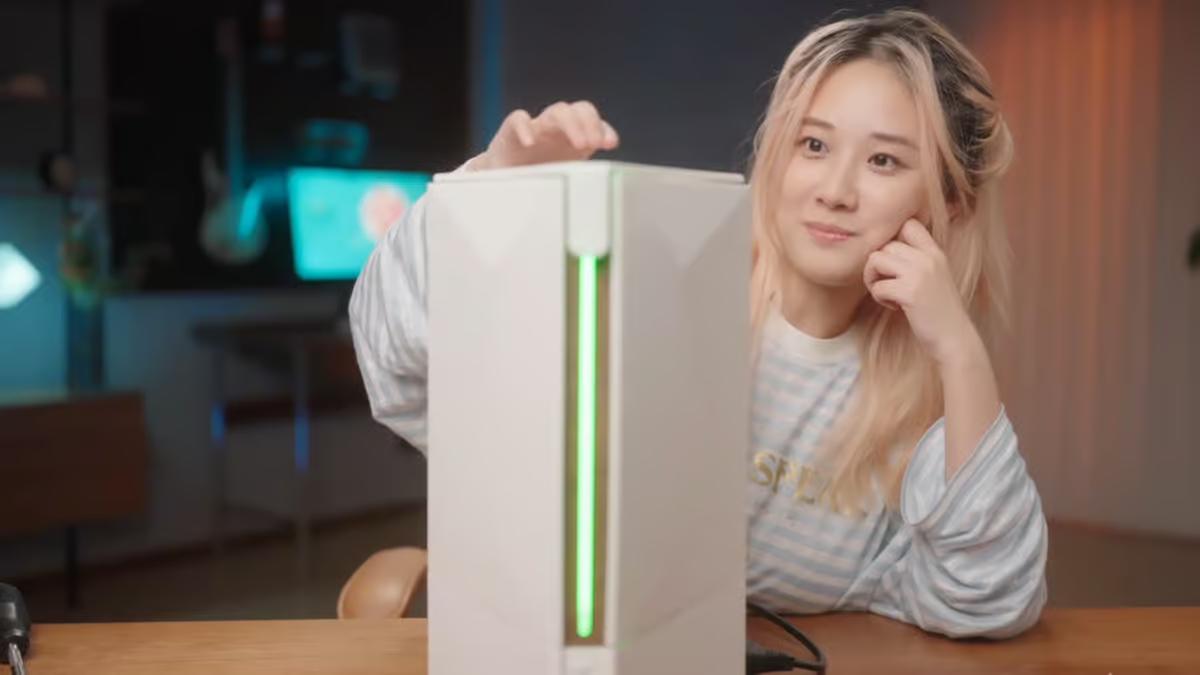 A sleek, triangular-shaped custom gaming console with a white exterior, inspired by the Apple Mac Pro design, featuring internal hardware from PlayStation 5, Xbox, and Nintendo Switch 2.